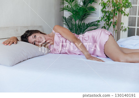 Beautiful woman in pajamas smiling in bedroom Beautiful woman in pajamas smiling in bedroom 130140191