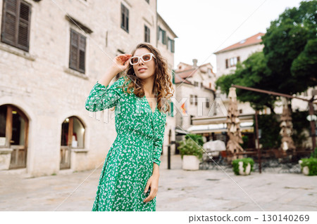 Happy female tourist in beautiful dress walking in the street of the city. Fashion style. Travel. 130140269