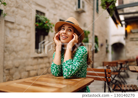 Young woman sitting by table of outdoor sidewalk cafe restaurant. People, fashion, lifestyle 130140270