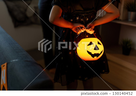 Halloween Celebration. Child holding glowing pumpkin lantern, festive atmosphere. 130140452