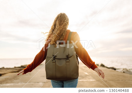 Portrait of woman enjoying a breezy day near a vibrant red lighthouse at sunset. Lifestyle concept. Portrait of woman enjoying a breezy day near a vibrant red lighthouse at sunset. Lifestyle concept. 130140488