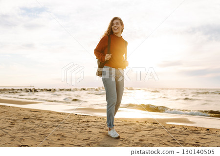 As she walked along the beach, the woman tourist adjusted her backpack, taking in the salty sea air As she walked along the beach, the woman tourist adjusted her backpack, taking in the salty sea air 130140505