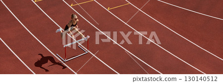 Female hurdler mid jump over hurdle on athletics track showing strength and focus. Banner Female hurdler mid jump over hurdle on athletics track showing strength and focus. Banner 130140512