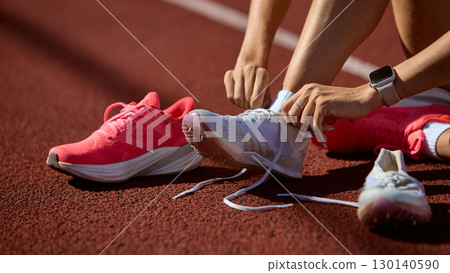 Close-up runner tying spikes on athletics track before hurdles race 130140590