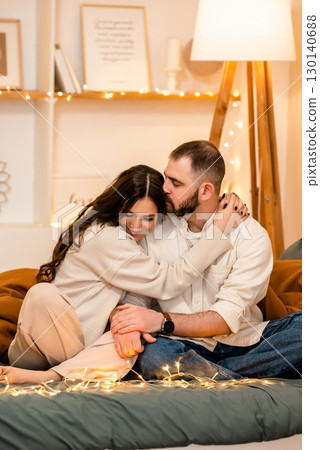 Couple Embracing on Cozy Bed with String Lights 130140688