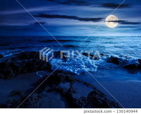 beach with sand at night. summer vacation at the seaside. beautiful seascape with calm waves in full moon light. landscape at the sea under sky with fluffy clouds 130140944
