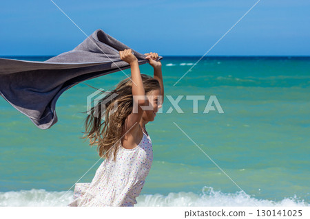 Little one having fun with towel by the ocean Little one having fun with towel by the ocean 130141025