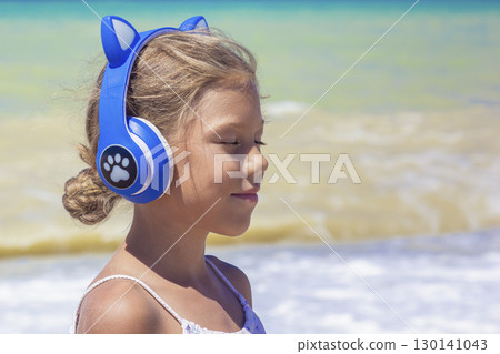 Profile of little girl with cat ears headphones on seashore Profile of little girl with cat ears headphones on seashore 130141043