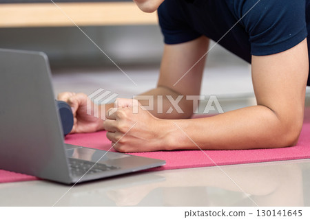Home Fitness. Young man doing plank exercise with laptop for online workout. 130141645