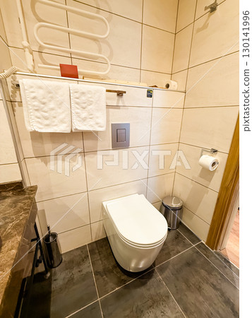 Modern bathroom with toilet, towel rack, and sanitary equipment. Cleanliness, hospitality, and comfort in hotel accommodation. 130141996