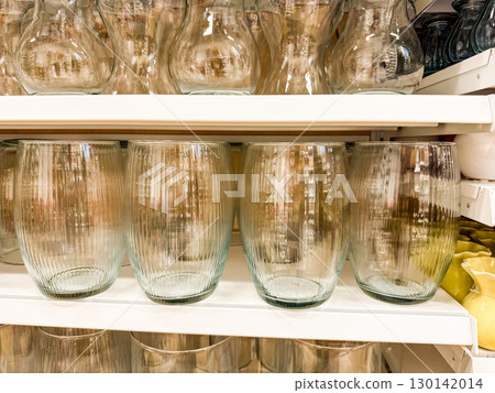 Glass vases arranged on store shelf. Interior decoration, elegance, and modern home styling with transparent accessories. Glass vases arranged on store shelf. Interior decoration, elegance, and modern home styling with transparent accessories. 130142014