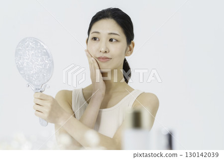 身穿背心的年輕女子，白色背景，手托著臉頰。美女 130142039