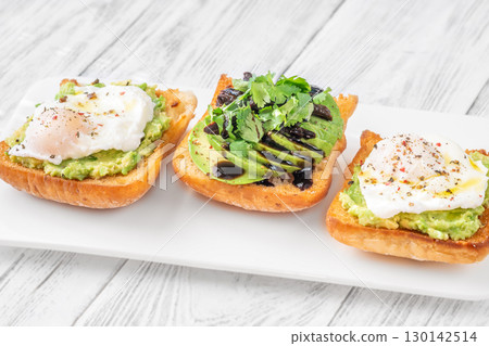 Ciabatta sandwiches with poached egg, avocado mash, sundried tomato and herbs 130142514