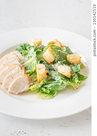 Classic Caesar salad topped with chicken breast served on clean white plate Classic Caesar salad topped with chicken breast served on clean white plate 130142519