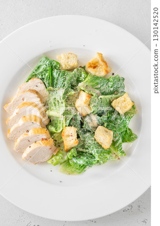 Classic Caesar salad topped with chicken breast served on clean white plate Classic Caesar salad topped with chicken breast served on clean white plate 130142520