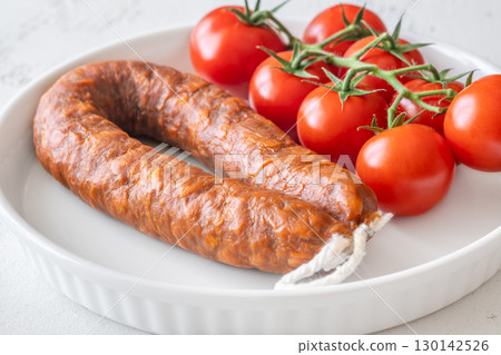 Curved Chorizo and Cherry Tomatoes Arranged Neatly on Minimal White Ceramic Plate 130142526
