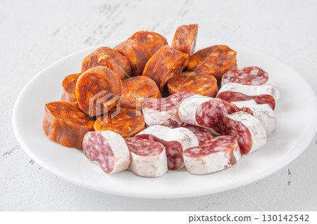 Assorted Spanish Chorizo and Fuet Sausage Slices on Minimal White Background 130142542