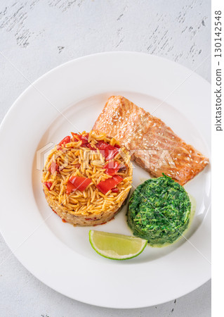 Elegant plated salmon with rice pilaf and creamy spinach on white round plate Elegant plated salmon with rice pilaf and creamy spinach on white round plate 130142548