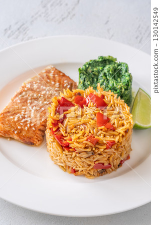 Elegant plated salmon with rice pilaf and creamy spinach on white round plate Elegant plated salmon with rice pilaf and creamy spinach on white round plate 130142549