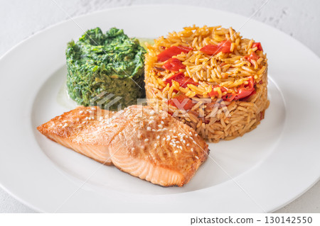 Elegant plated salmon with rice pilaf and creamy spinach on white round plate Elegant plated salmon with rice pilaf and creamy spinach on white round plate 130142550