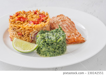 Elegant plated salmon with rice pilaf and creamy spinach on white round plate 130142551