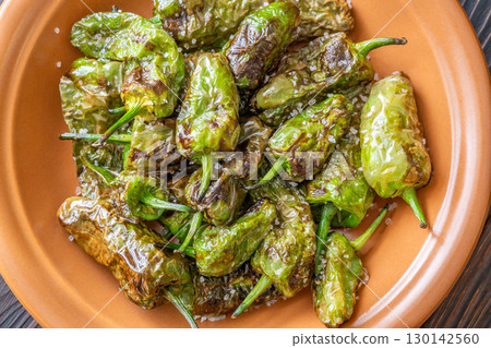 Terracotta bowl of Pimientos de Padron sprinkled with coarse sea salt 130142560