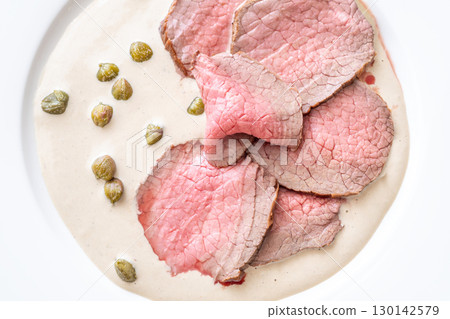 Elegant Vitello Tonnato with scattered capers and creamy sauce on plate 130142579