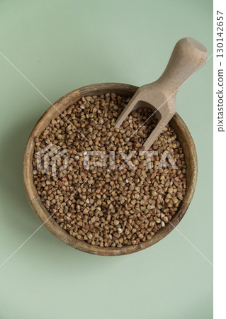 Raw buckwheat porridge in green background copy space. Whole spelt grain species. High protein fiber-rich vegan plant based food ingredient. Gluten free superfood healthy nutritional dietary Raw buckwheat porridge in green background copy space. Whole spelt grain species. High protein fiber-rich vegan plant based food ingredient. Gluten free superfood healthy nutritional dietary 130142657