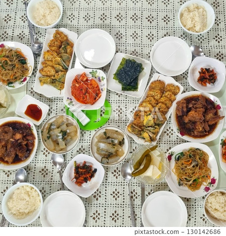 The images show a large and complete Korean home-cooked meal, known as a 'hansang,' with a variety of traditional side dishes, including rice, kimchi, japchae, and various jeon. 130142686