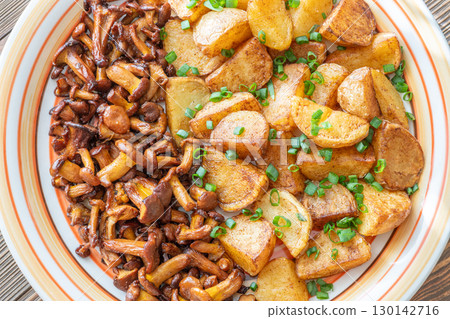 Fried potatoes chanterelle mushrooms seasoned paprika rustic wooden table plate 130142716