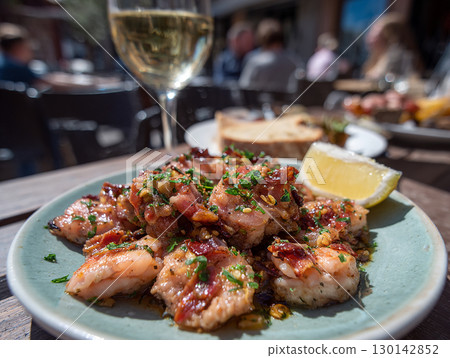 Grilled octopus tapas with garlic and herbs served with lemon wedge and white wine 130142852