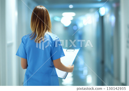 Nurses and medical records walking down a hospital corridor Nurses and medical records walking down a hospital corridor 130142935