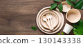 Paper eco-friendly tableware set on wooden background and green leaves as a decoration next to, copy space. 130143338