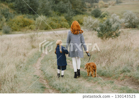 Mother and her daughter playing with dog. Family in autumn park. Pet, domestic animal and lifestyle concept. Autumn time. Mother and her daughter playing with dog. Family in autumn park. Pet, domestic animal and lifestyle concept. Autumn time. 130143525