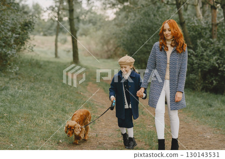 Mother and her daughter playing with dog. Family in autumn park. Pet, domestic animal and lifestyle concept. Autumn time. Mother and her daughter playing with dog. Family in autumn park. Pet, domestic animal and lifestyle concept. Autumn time. 130143531
