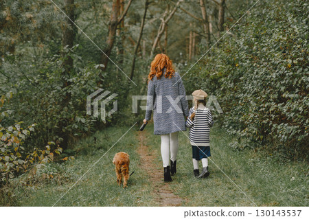 Mother and her daughter playing with dog. Family in autumn park. Pet, domestic animal and lifestyle concept. Autumn time. 130143537