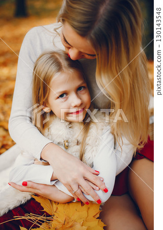 Fashionable mother with daughter. Family in a autumn park. 130143548