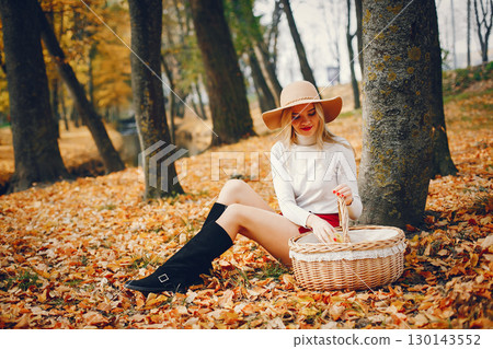 Beautiful woman in a park. Stylish girl in a brown hat 130143552