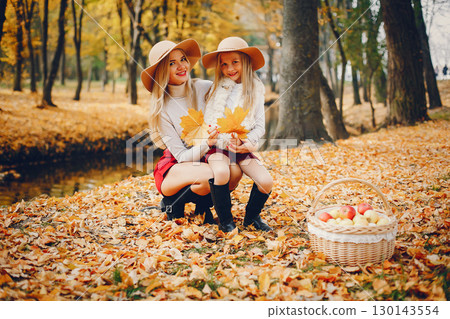Fashionable mother with daughter. Family in a autumn park. 130143554