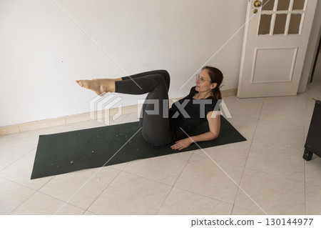 Woman doing fitness exercises at home on yoga mat 130144977