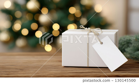 Christmas and New Year mockup of white gift box with blank tag on festive background and copy space, warm wooden color tone. 130145500