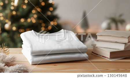 Christmas and New Year mockup of plain white folded stack t-shirt on wooden table, festive background and copy space, warm color tone. 130145648