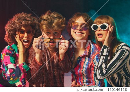 Smiling retro group in bold disco costumes celebrating friendship 130146138