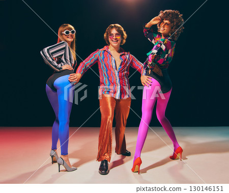 Retro fashion trio in colorful disco outfits striking confident pose Retro fashion trio in colorful disco outfits striking confident pose 130146151