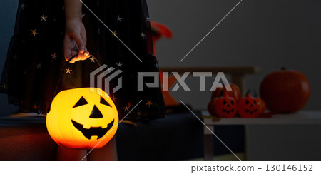 Halloween. Child holding glowing pumpkin bucket for trick-or-treating. 130146152
