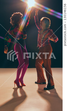 Man and woman dancing in bold disco costumes under stage light Man and woman dancing in bold disco costumes under stage light 130146156