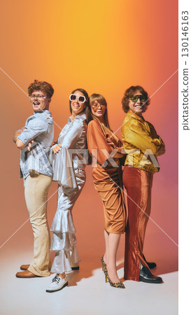 Retro group posing back to back in disco fashion on orange background 130146163