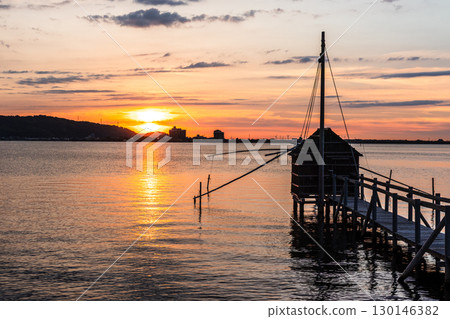 Evening view of Lake Togo: Sunset and a lookout hut for four-hand net fishing Evening view of Lake Togo: Sunset and a lookout hut for four-hand net fishing 130146382