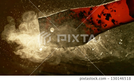Close-up of glowing hot iron being quenched in cold water. Concept of metal forging and cooling. Close-up of glowing hot iron being quenched in cold water. Concept of metal forging and cooling. 130146518