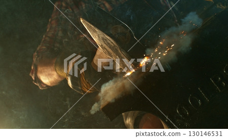 The blacksmith manually forging the molten metal on the anvil in smithy with spark fireworks 130146531